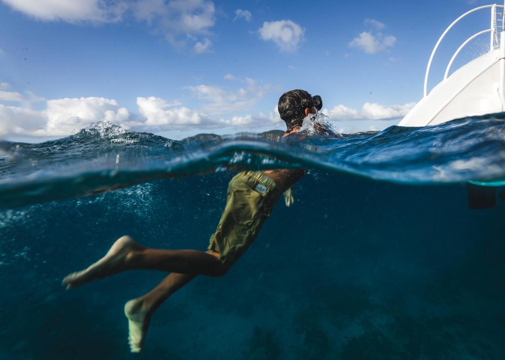 Person snorkeling near the surface in clear blue water with a boat in the background.