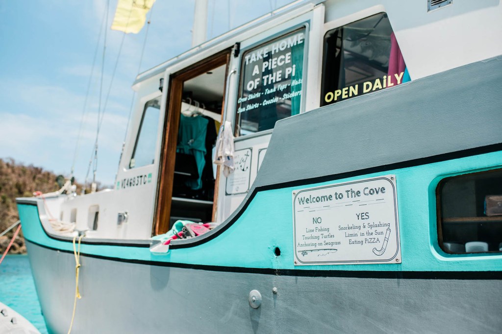 Docked boat with signs reading 'Welcome to The Cove' and 'Open Daily' on a sunny day.