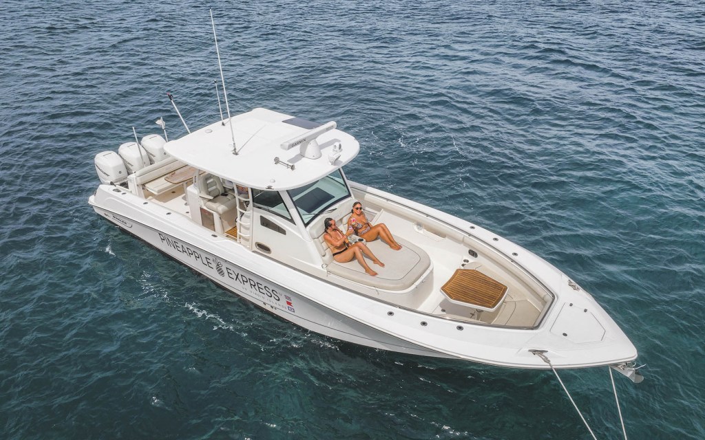 Two people relaxing on a white motorboat in the ocean.