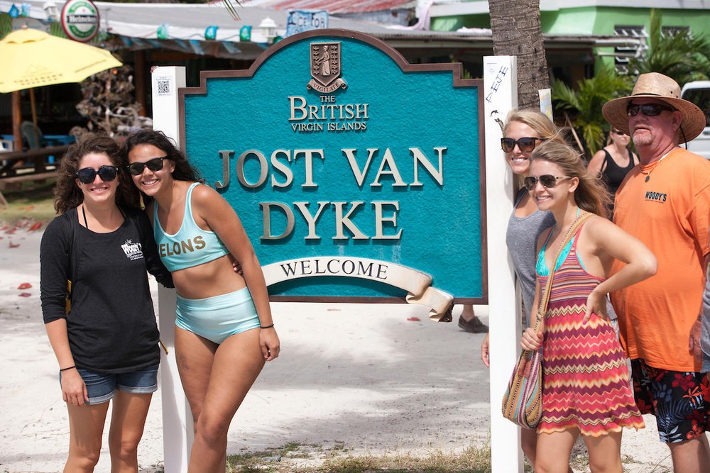 Group of people posing in front of Jost Van Dyke welcome sign in the British Virgin Islands.