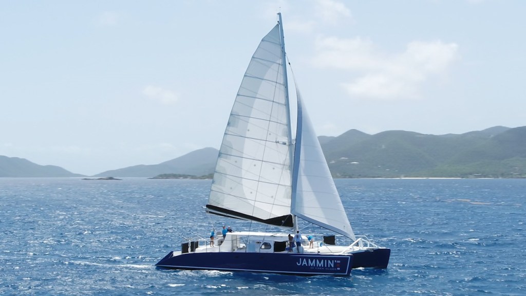 Sailboat on the ocean with mountains in the background under a clear sky.