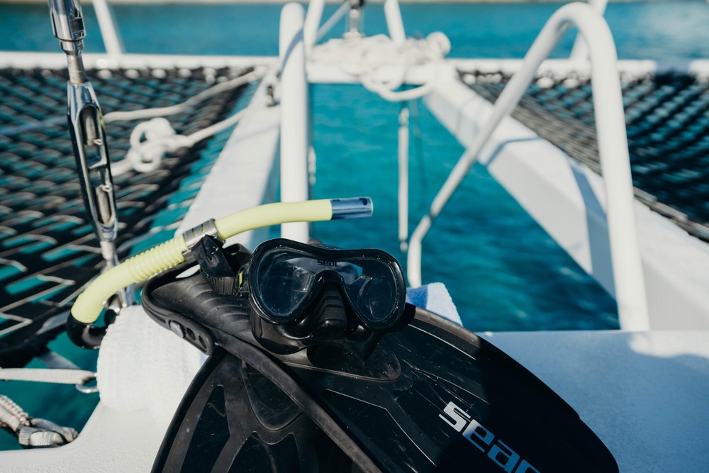 Snorkel gear on a boat's deck above clear turquoise water.