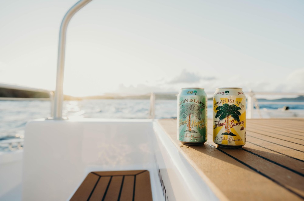 Two cans on a boat deck with ocean and sunset in the background.