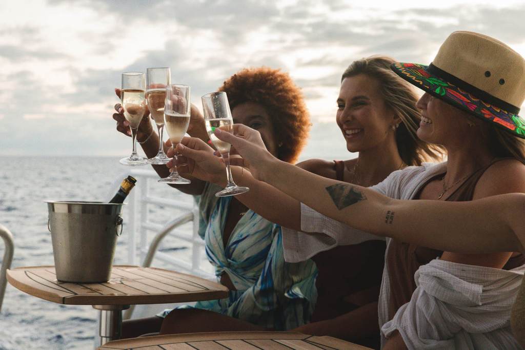 Three people toasting with champagne glasses on a boat.