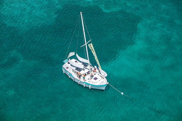 Aerial view of a sailboat anchored in turquoise water.