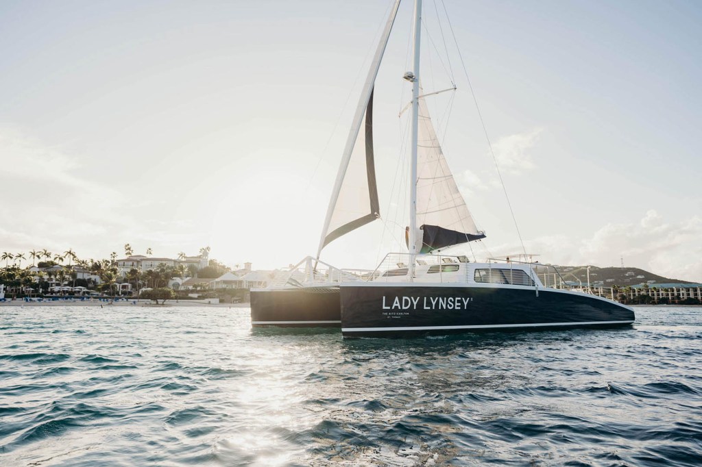 Sailboat named 'Lady Lynsey' sailing on water at sunset.