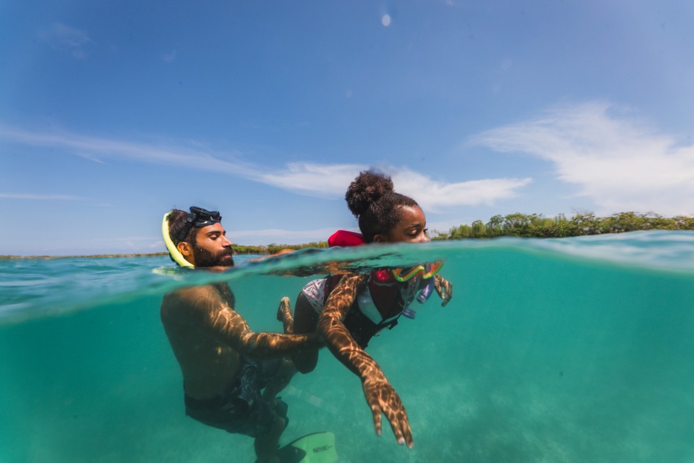 Two people snorkeling in clear blue water under a sunny sky.