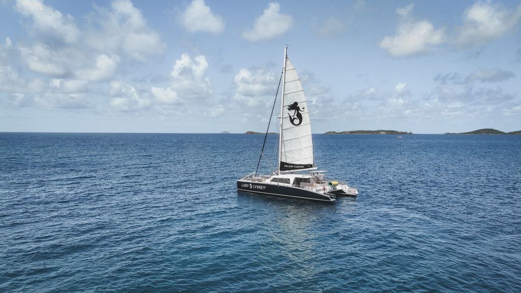 Sailboat on a calm ocean with a clear sky and distant islands.