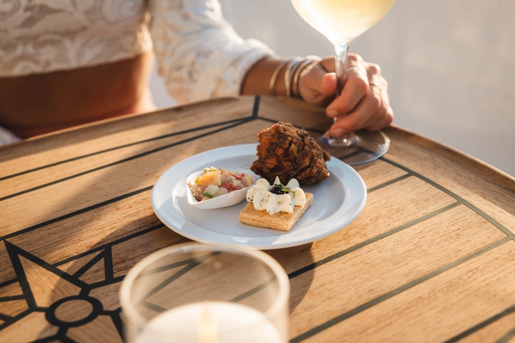 Plate with appetizers and a glass of white wine on a wooden table.
