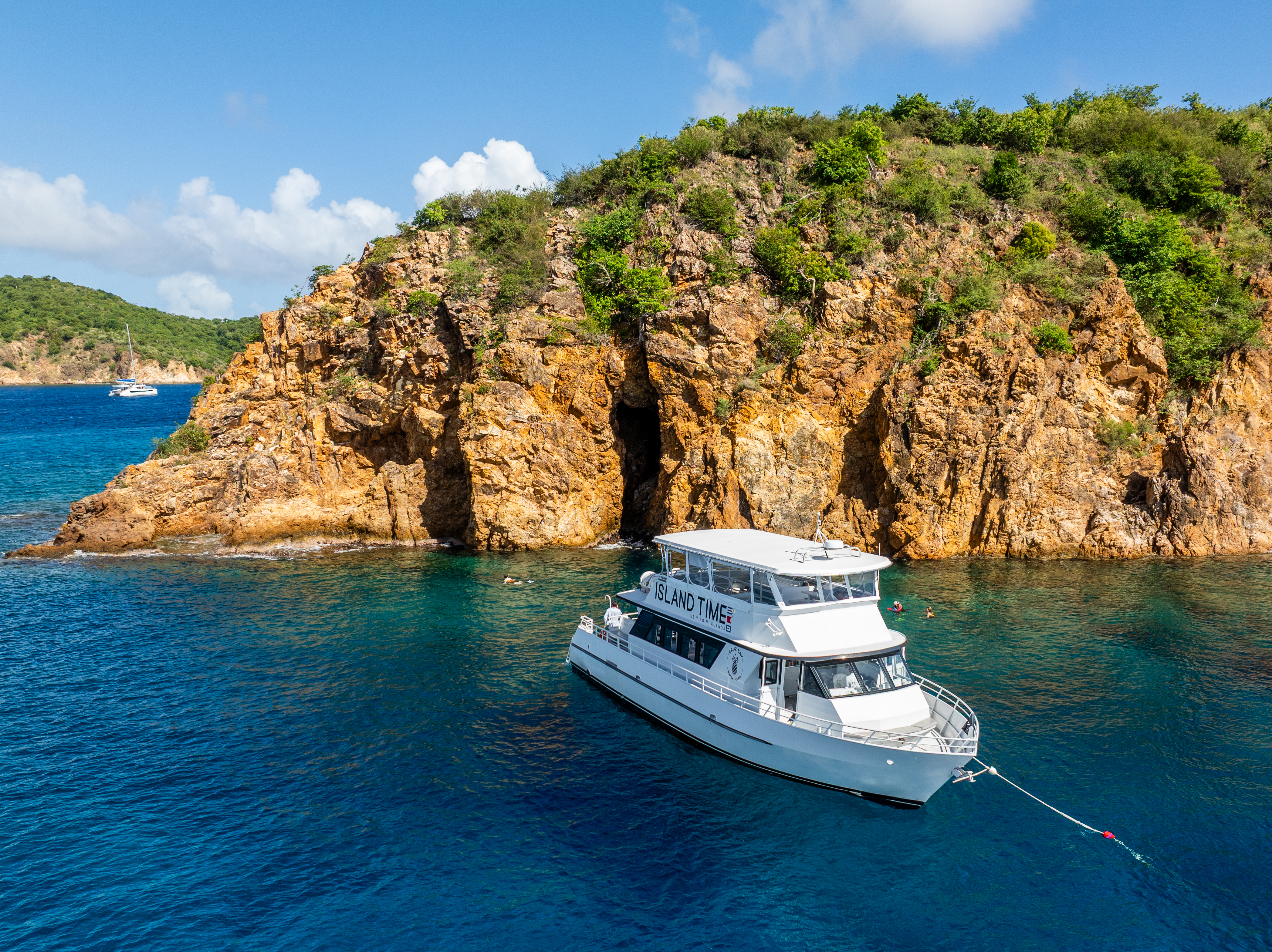A boat anchored near a rocky island with green vegetation.