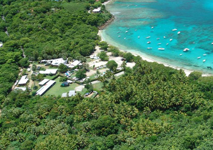 Aerial view of a coastal village with green forests and turquoise water.