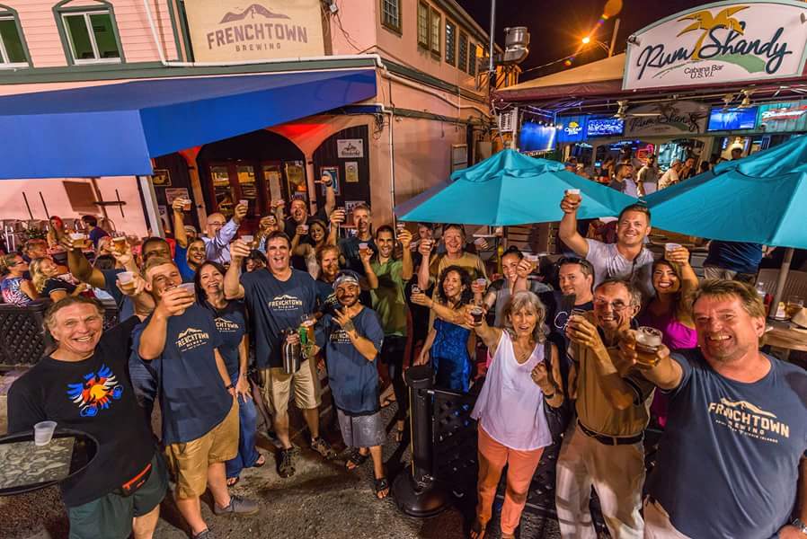Group of people posing outside a restaurant at night, with blue umbrellas and festive atmosphere.