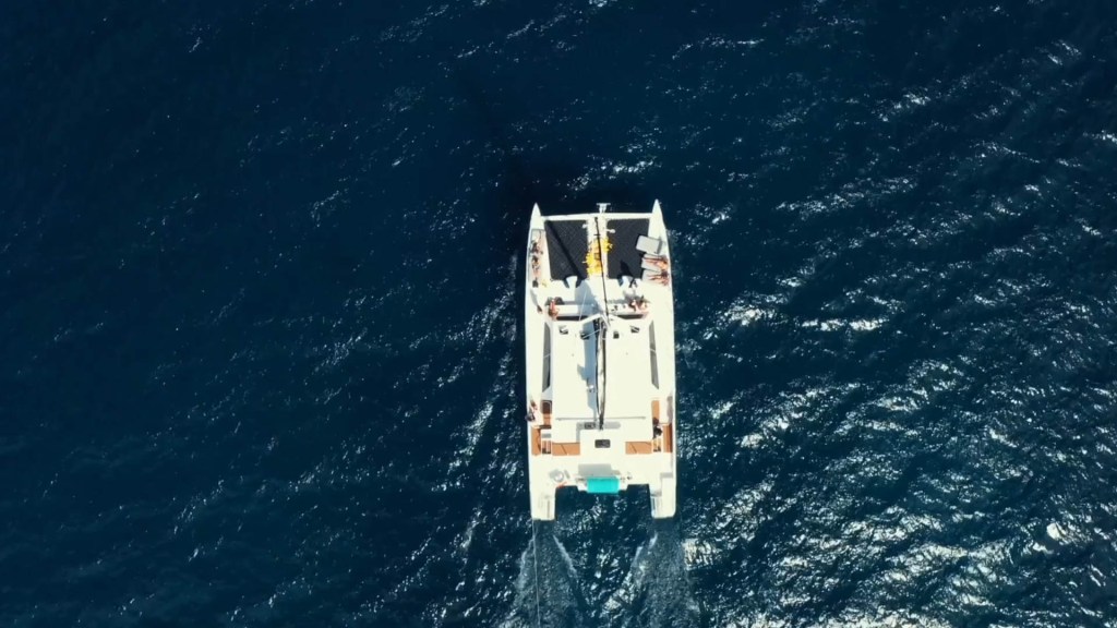 Aerial view of a catamaran on deep blue ocean water.